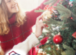 A joyful moment of two young girls wearing Santa hats as they decorate a beautifully lit Christmas tree