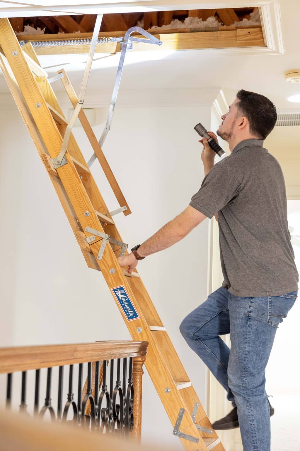 home inspector walking up an interior pull down ladder to get into the attic