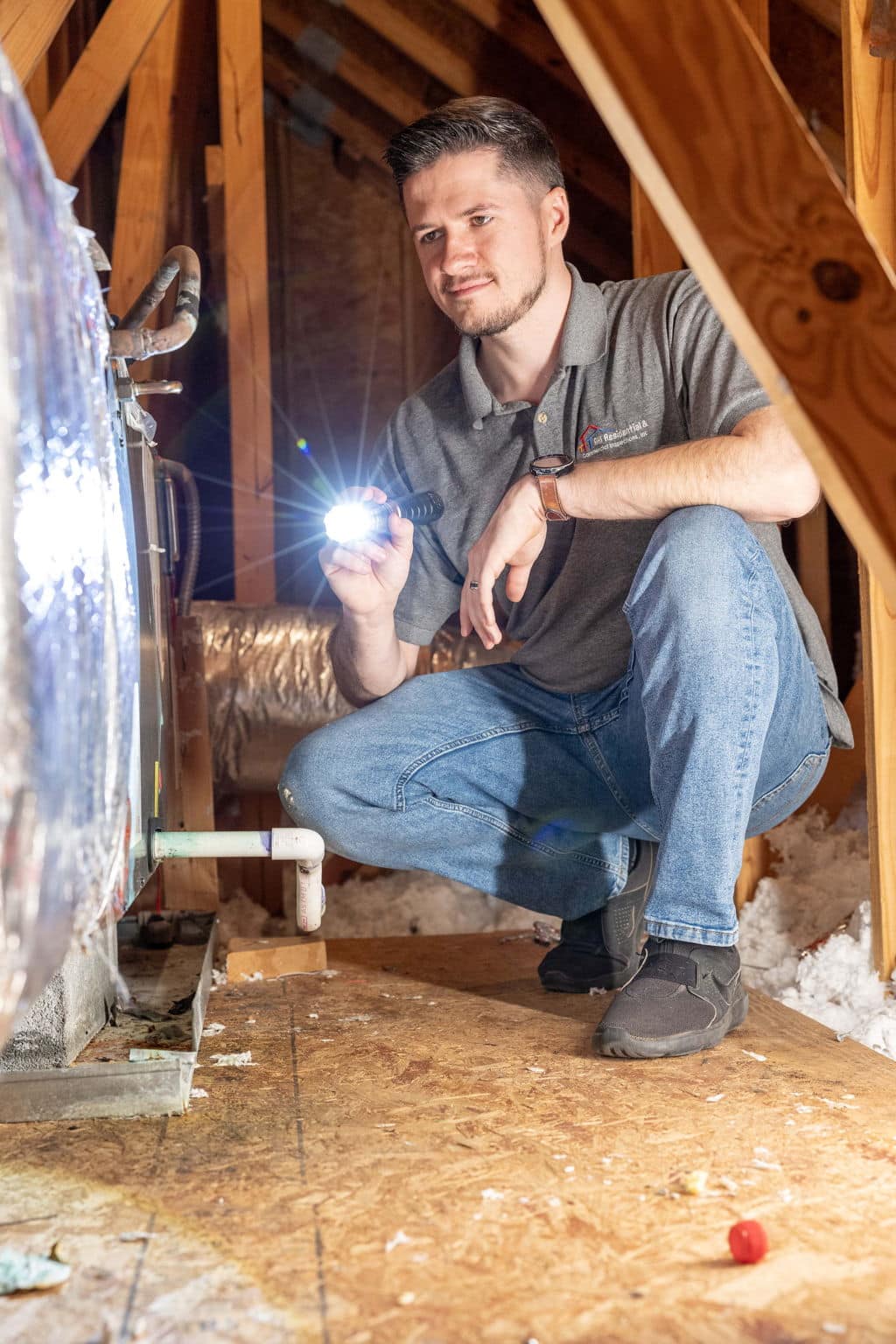 home inspector in the attic with his flashlight on looking at hvac ductwork for proper installation