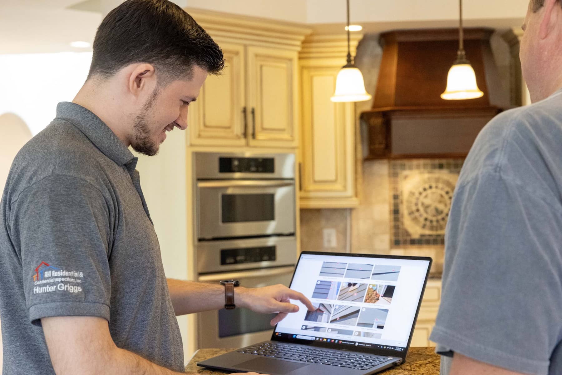 inspector showing the inspection report on a laptop inside the home's kitchen
