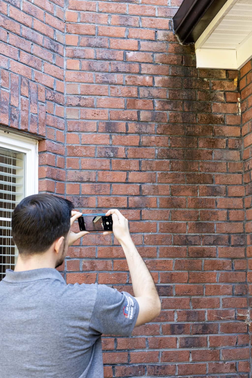 Home inspector taking a picture of water staining on the exterior of a home