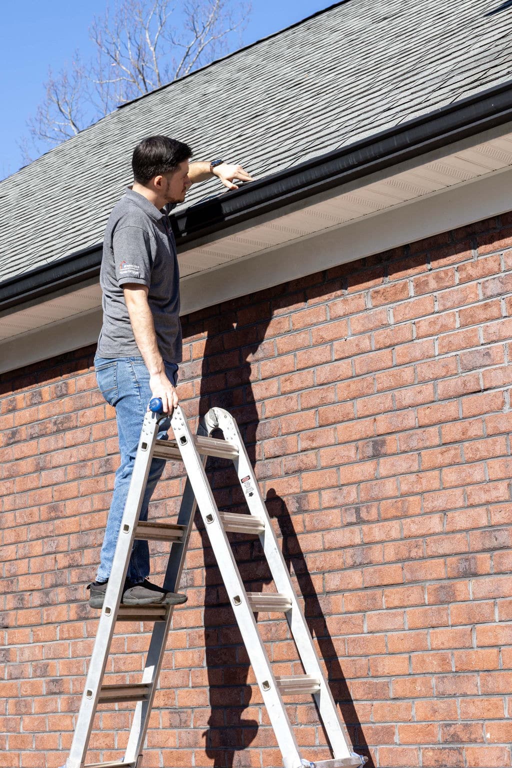 home inspector looking at the edge of the roof line to see if shingles are properly secured