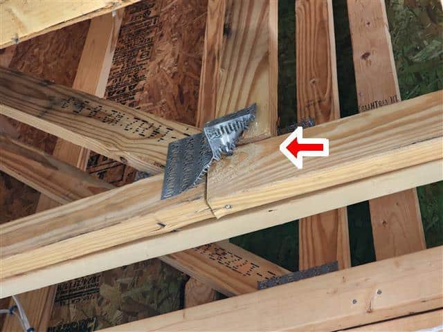 Metal truss connector plate improperly installed or damaged on roof truss connection