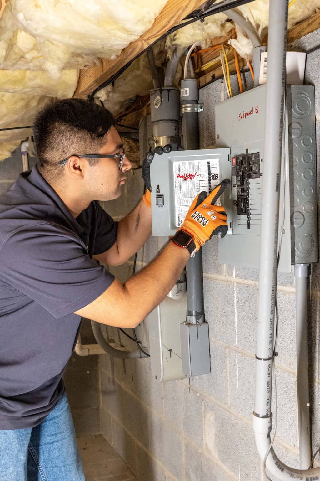 inspector looking at electrical panel underneath a house