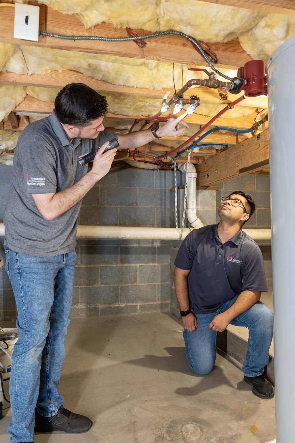Home inspectors looking at plumbing while underneath a house