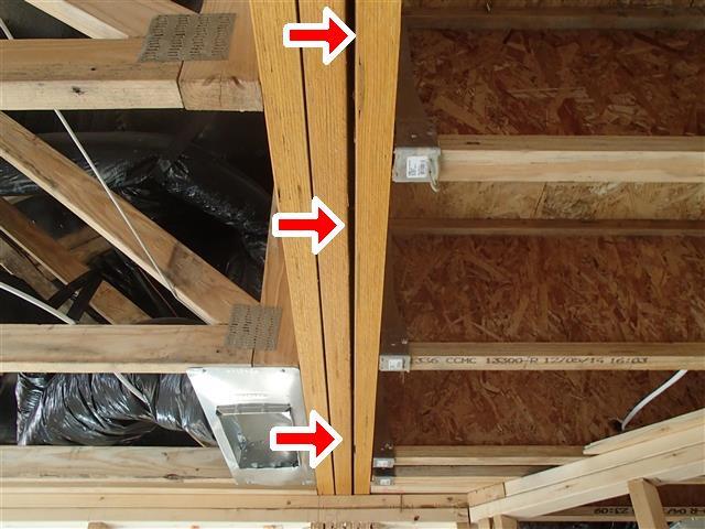 Ceiling joists with multiple splits and damage in wood members indicated by three red arrows