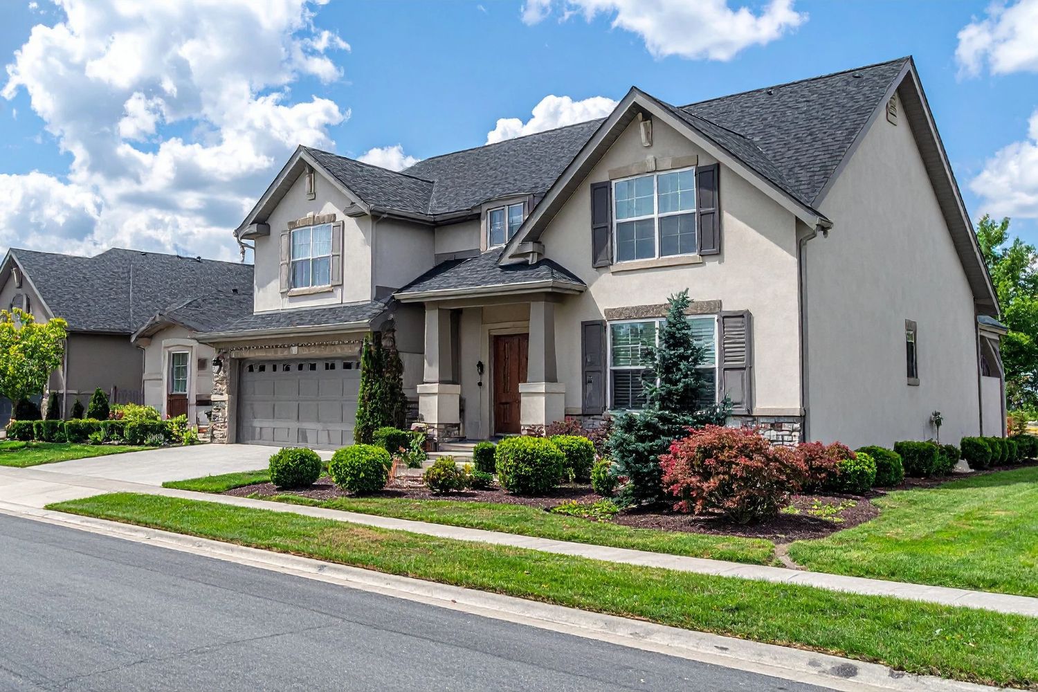 Exterior of a single-family residential home in Charlotte, NC, featuring stucco siding, stone accents, and a landscaped yard.