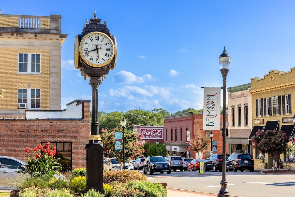 Vintage ornamental street clock standing along Main Street in downtown Belmont, North Carolina, surrounded by historic brick storefronts.