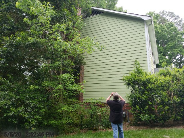 All the Problems Inspectors Commonly Find in NC Homes 4 A person standing in a grassy yard, looking up to take a photo of all the problems caught during a home inspection.