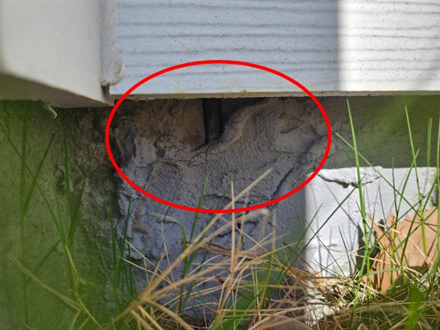 Slab edge broken out around a foundation bolt at the rear of Home D