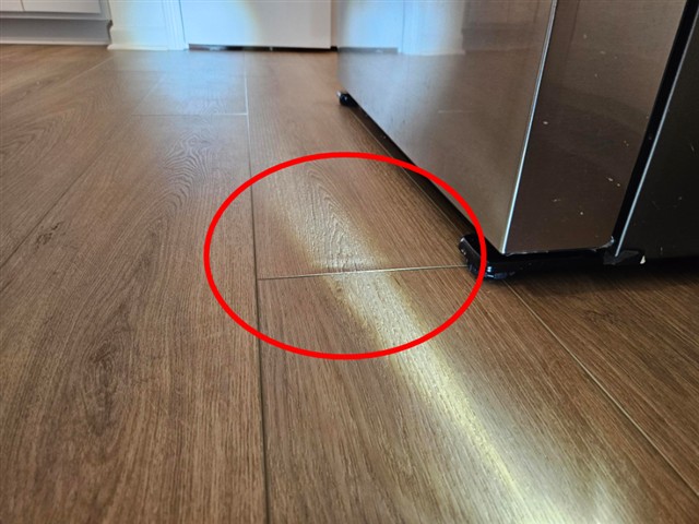 Buckled floating floor plank in the kitchen of Home B