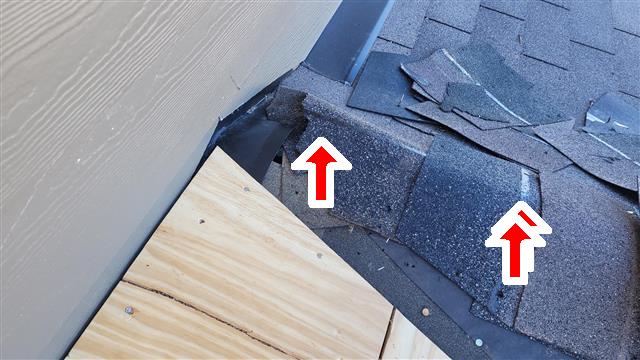 Torn and damaged shingles where the roof meets a wall on Home H