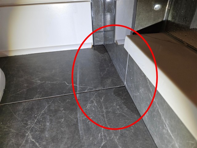 Missing grout at the base of the tile shower in Home C