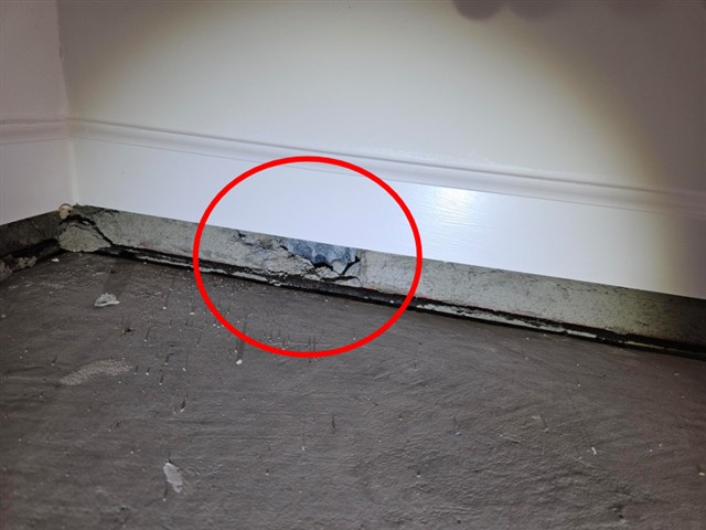 Damaged concrete foundation along the base of the garage wall in Home D