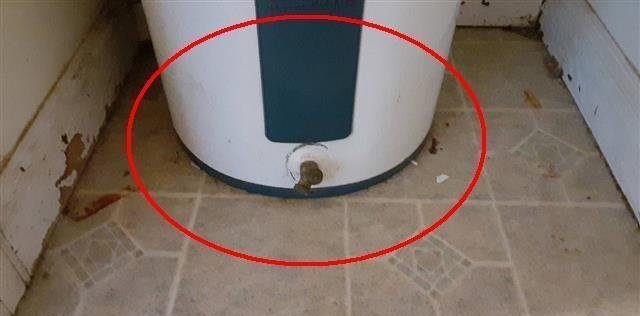 Home B: no drain pan under the water heater, with past water damage behind it