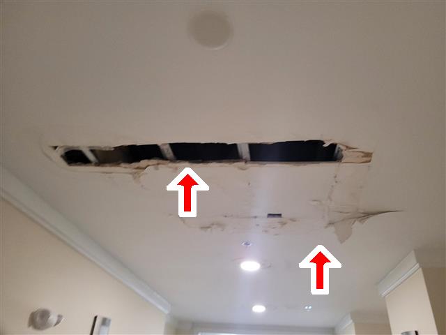 Opened drywall ceiling with peeling paper and stains from a water leak in a condo