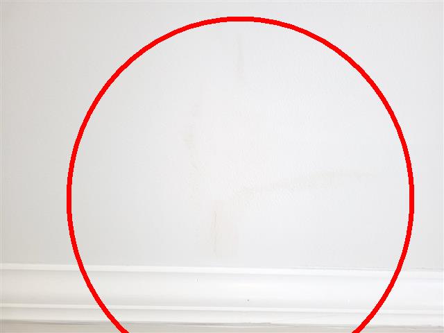 Faint water stains on a painted wall above baseboard trim in a condo