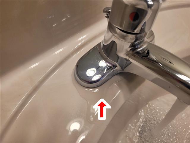 Water leaking from the base of a bathroom sink faucet during a home inspection