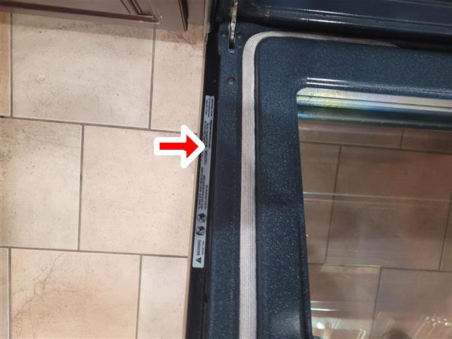 Range anti-tip warning label on an oven door frame
