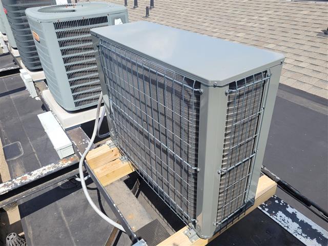 Rooftop HVAC condenser units sitting on wood blocks on a flat condo roof