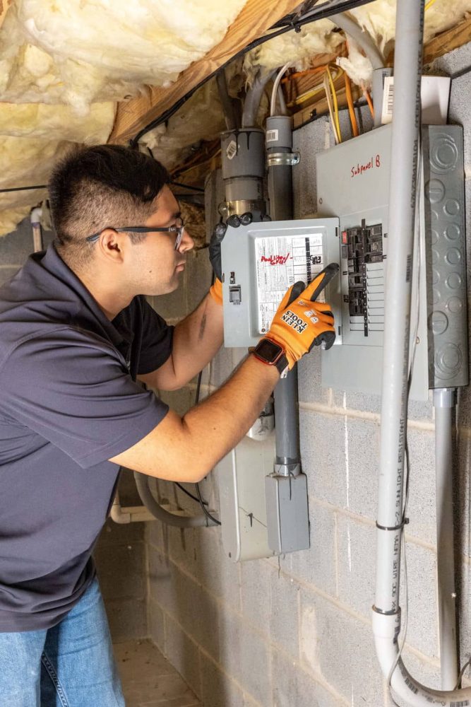 inspector looking at electrical panel underneath a house